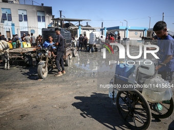 Palestinians are filling containers with water at a desalination plant in Deir el-Balah in the central Gaza Strip on July 17, 2024, amid the...