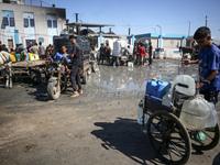 Palestinians are filling containers with water at a desalination plant in Deir el-Balah in the central Gaza Strip on July 17, 2024, amid the...