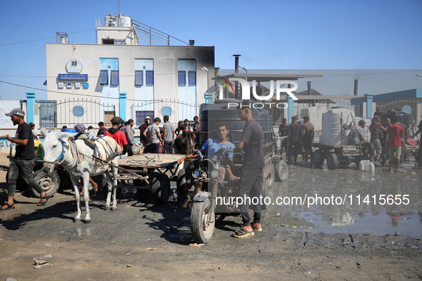 Palestinians are filling containers with water at a desalination plant in Deir el-Balah in the central Gaza Strip on July 17, 2024, amid the...