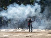 People are running as police are firing teargas during a coffin rally of anti-quota protesters at the University of Dhaka, in Dhaka, Banglad...