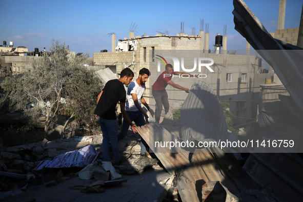 Palestinians are inspecting a house destroyed in an Israeli strike, amid the Israel-Hamas conflict, in Al-Zawaida, central Gaza Strip, on Ju...