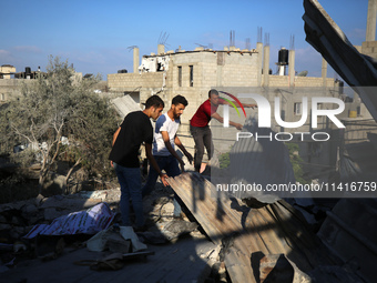 Palestinians are inspecting a house destroyed in an Israeli strike, amid the Israel-Hamas conflict, in Al-Zawaida, central Gaza Strip, on Ju...