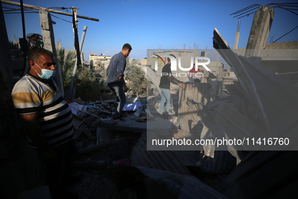 Palestinians are inspecting a house destroyed in an Israeli strike, amid the Israel-Hamas conflict, in Al-Zawaida, central Gaza Strip, on Ju...