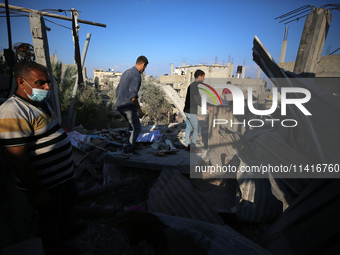 Palestinians are inspecting a house destroyed in an Israeli strike, amid the Israel-Hamas conflict, in Al-Zawaida, central Gaza Strip, on Ju...