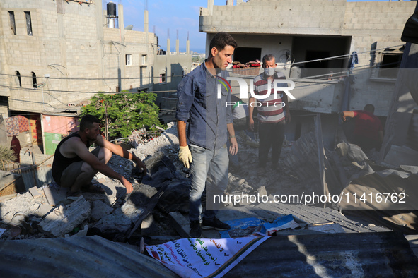 Palestinians are inspecting a house destroyed in an Israeli strike, amid the Israel-Hamas conflict, in Al-Zawaida, central Gaza Strip, on Ju...