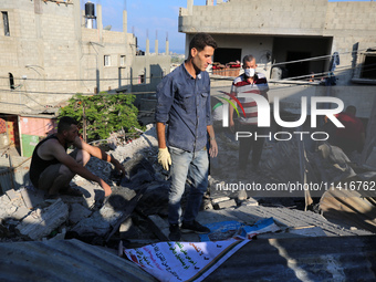 Palestinians are inspecting a house destroyed in an Israeli strike, amid the Israel-Hamas conflict, in Al-Zawaida, central Gaza Strip, on Ju...