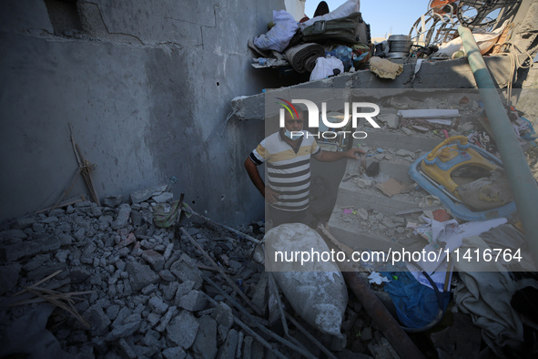 Palestinians are inspecting a house destroyed in an Israeli strike, amid the Israel-Hamas conflict, in Al-Zawaida, central Gaza Strip, on Ju...