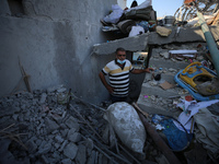 Palestinians are inspecting a house destroyed in an Israeli strike, amid the Israel-Hamas conflict, in Al-Zawaida, central Gaza Strip, on Ju...