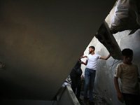 Palestinians are inspecting a house destroyed in an Israeli strike, amid the Israel-Hamas conflict, in Al-Zawaida, central Gaza Strip, on Ju...