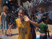 Displaced Palestinian children are playing together in the water in swimming pools in a makeshift camp during hot weather in Deir el-Balah,...