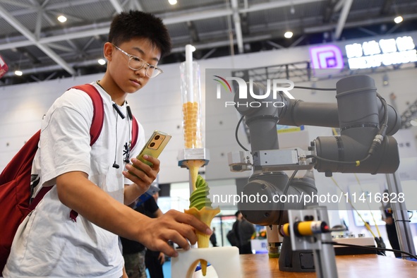 A student is experiencing an intelligent robot ice cream machine at the 26th China Qingdao International Industrial Automation Technology an...