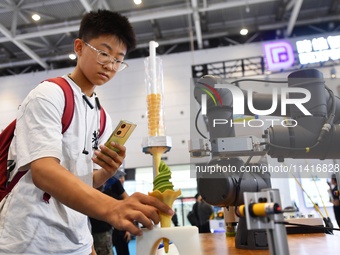 A student is experiencing an intelligent robot ice cream machine at the 26th China Qingdao International Industrial Automation Technology an...