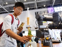 A student is experiencing an intelligent robot ice cream machine at the 26th China Qingdao International Industrial Automation Technology an...