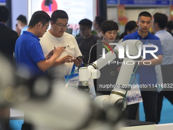 Participants are looking at a composite robot displayed by a company at the 26th China Qingdao International Industrial Automation Technolog...