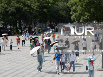 Tourists are using umbrellas to take a sightseeing tour at Chen Yi Square on the Bund in Huangpu district of Shanghai, China, on July 18, 20...