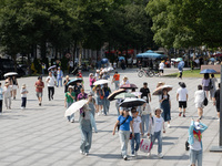 Tourists are using umbrellas to take a sightseeing tour at Chen Yi Square on the Bund in Huangpu district of Shanghai, China, on July 18, 20...