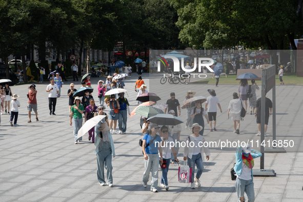 Tourists are using umbrellas to take a sightseeing tour at Chen Yi Square on the Bund in Huangpu district of Shanghai, China, on July 18, 20...