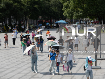 Tourists are using umbrellas to take a sightseeing tour at Chen Yi Square on the Bund in Huangpu district of Shanghai, China, on July 18, 20...