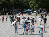 Tourists are using umbrellas to take a sightseeing tour at Chen Yi Square on the Bund in Huangpu district of Shanghai, China, on July 18, 20...