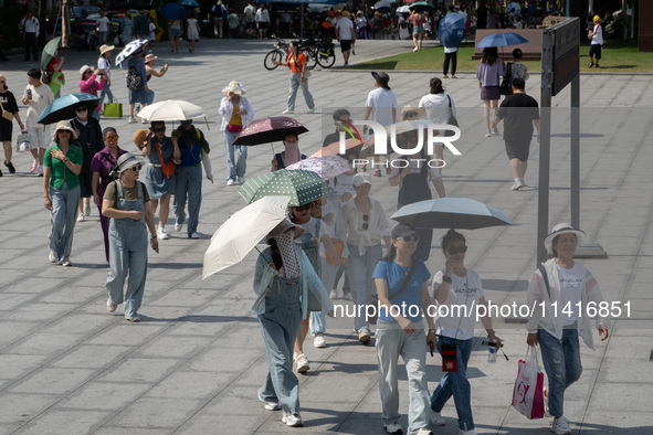 Tourists are using umbrellas to take a sightseeing tour at Chen Yi Square on the Bund in Huangpu district of Shanghai, China, on July 18, 20...