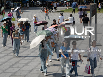 Tourists are using umbrellas to take a sightseeing tour at Chen Yi Square on the Bund in Huangpu district of Shanghai, China, on July 18, 20...