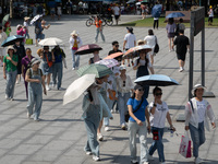 Tourists are using umbrellas to take a sightseeing tour at Chen Yi Square on the Bund in Huangpu district of Shanghai, China, on July 18, 20...