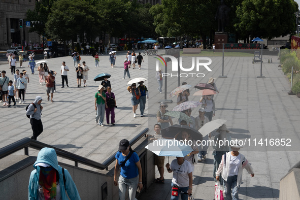 Tourists are using umbrellas to take a sightseeing tour at Chen Yi Square on the Bund in Huangpu district of Shanghai, China, on July 18, 20...