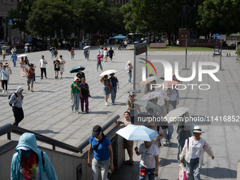 Tourists are using umbrellas to take a sightseeing tour at Chen Yi Square on the Bund in Huangpu district of Shanghai, China, on July 18, 20...