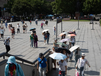 Tourists are using umbrellas to take a sightseeing tour at Chen Yi Square on the Bund in Huangpu district of Shanghai, China, on July 18, 20...