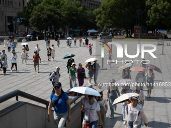 Tourists are using umbrellas to take a sightseeing tour at Chen Yi Square on the Bund in Huangpu district of Shanghai, China, on July 18, 20...