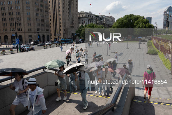 Tourists are using umbrellas to take a sightseeing tour at Chen Yi Square on the Bund in Huangpu district of Shanghai, China, on July 18, 20...