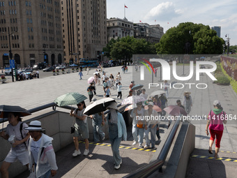 Tourists are using umbrellas to take a sightseeing tour at Chen Yi Square on the Bund in Huangpu district of Shanghai, China, on July 18, 20...