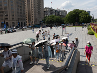 Tourists are using umbrellas to take a sightseeing tour at Chen Yi Square on the Bund in Huangpu district of Shanghai, China, on July 18, 20...