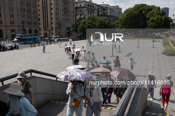 Tourists are using umbrellas to take a sightseeing tour at Chen Yi Square on the Bund in Huangpu district of Shanghai, China, on July 18, 20...