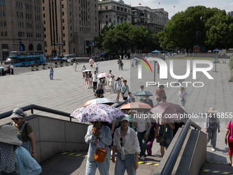 Tourists are using umbrellas to take a sightseeing tour at Chen Yi Square on the Bund in Huangpu district of Shanghai, China, on July 18, 20...