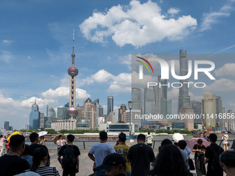 Tourists are using umbrellas to take a sightseeing tour on the Bund in Huangpu district in Shanghai, China, on July 18, 2024. (