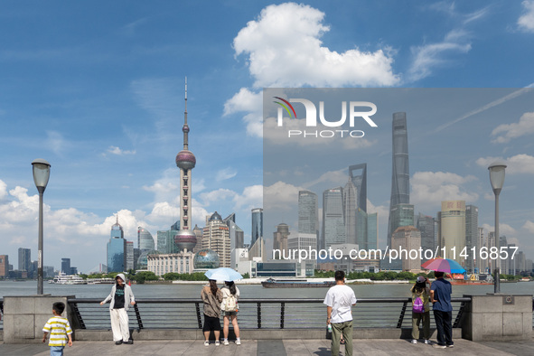 Tourists are using umbrellas to take a sightseeing tour on the Bund in Huangpu district in Shanghai, China, on July 18, 2024. 