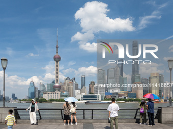 Tourists are using umbrellas to take a sightseeing tour on the Bund in Huangpu district in Shanghai, China, on July 18, 2024. (