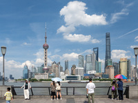 Tourists are using umbrellas to take a sightseeing tour on the Bund in Huangpu district in Shanghai, China, on July 18, 2024. (