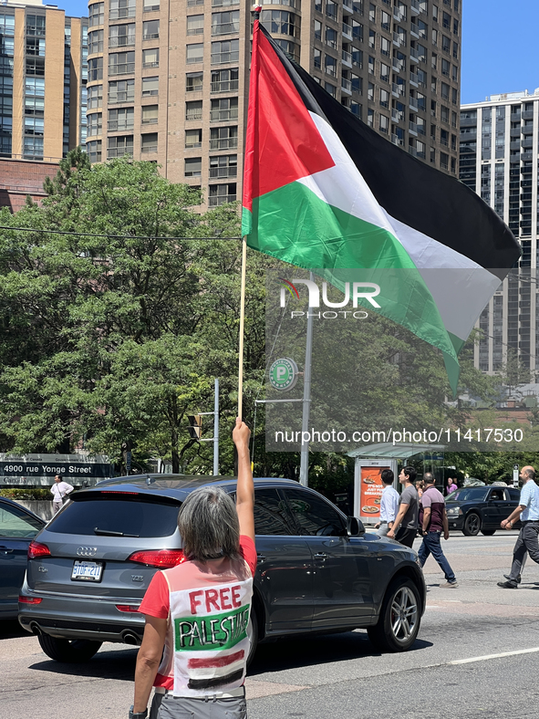 A woman is waving a large Palestinian flag during a Pro-Palestinian rally amid the Israel-Hamas conflict in Toronto, Ontario, Canada, on Jul...