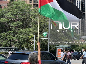 A woman is waving a large Palestinian flag during a Pro-Palestinian rally amid the Israel-Hamas conflict in Toronto, Ontario, Canada, on Jul...