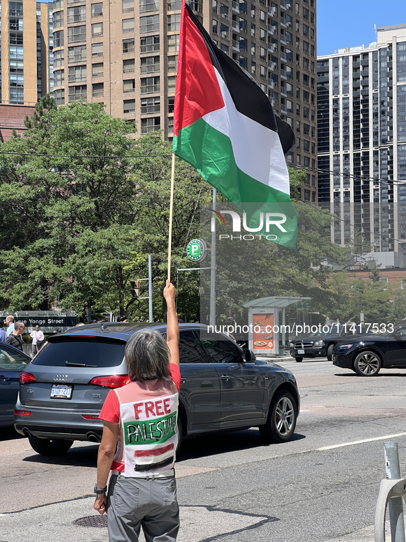 A woman is waving a large Palestinian flag during a Pro-Palestinian rally amid the Israel-Hamas conflict in Toronto, Ontario, Canada, on Jul...