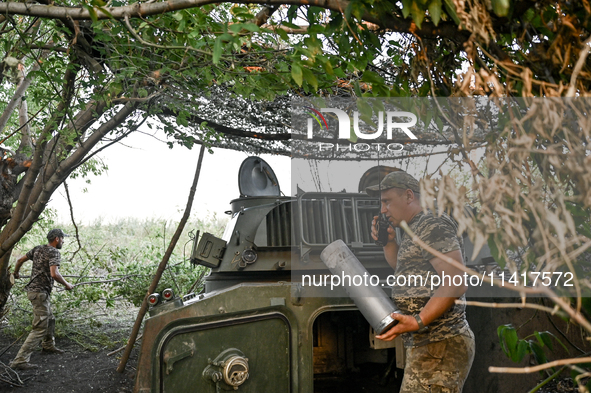 Andrii, a commander of an artillery crew of the 24th King Danylo Separate Mechanized Brigade, is using a handheld transceiver during a comba...