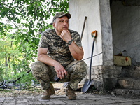 Andrii, a commander of an artillery crew of the 24th King Danylo Separate Mechanized Brigade, is holding a handheld transceiver while squatt...