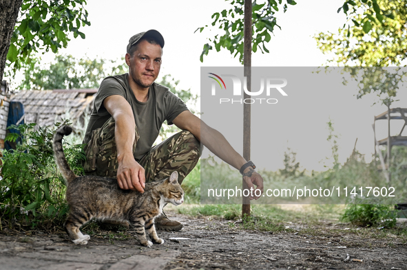 A serviceman of the 24th King Danylo Separate Mechanized Brigade, who goes by the call sign of Myron, is petting a cat at combat positions n...