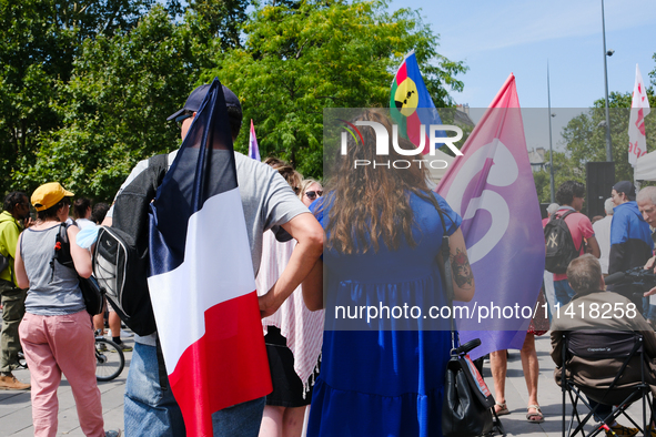 At the CGT rally, some unions are calling for a strike for the Olympic Games, and two activists are holding flags of France and La France In...