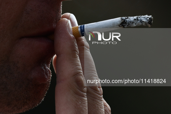 A person smokes a cigarette in Krakow, Poland on July 18, 2024. 