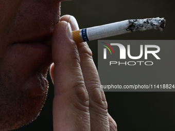 A person smokes a cigarette in Krakow, Poland on July 18, 2024. (