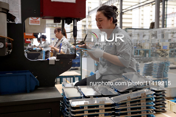 Workers are making battery pack accessories for new energy vehicles on an automated machine tool at an automated sheet metal workshop of an...