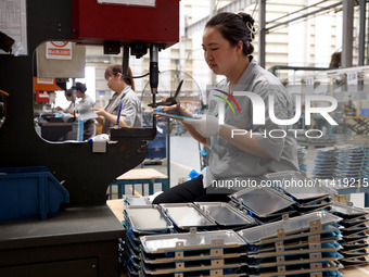 Workers are making battery pack accessories for new energy vehicles on an automated machine tool at an automated sheet metal workshop of an...